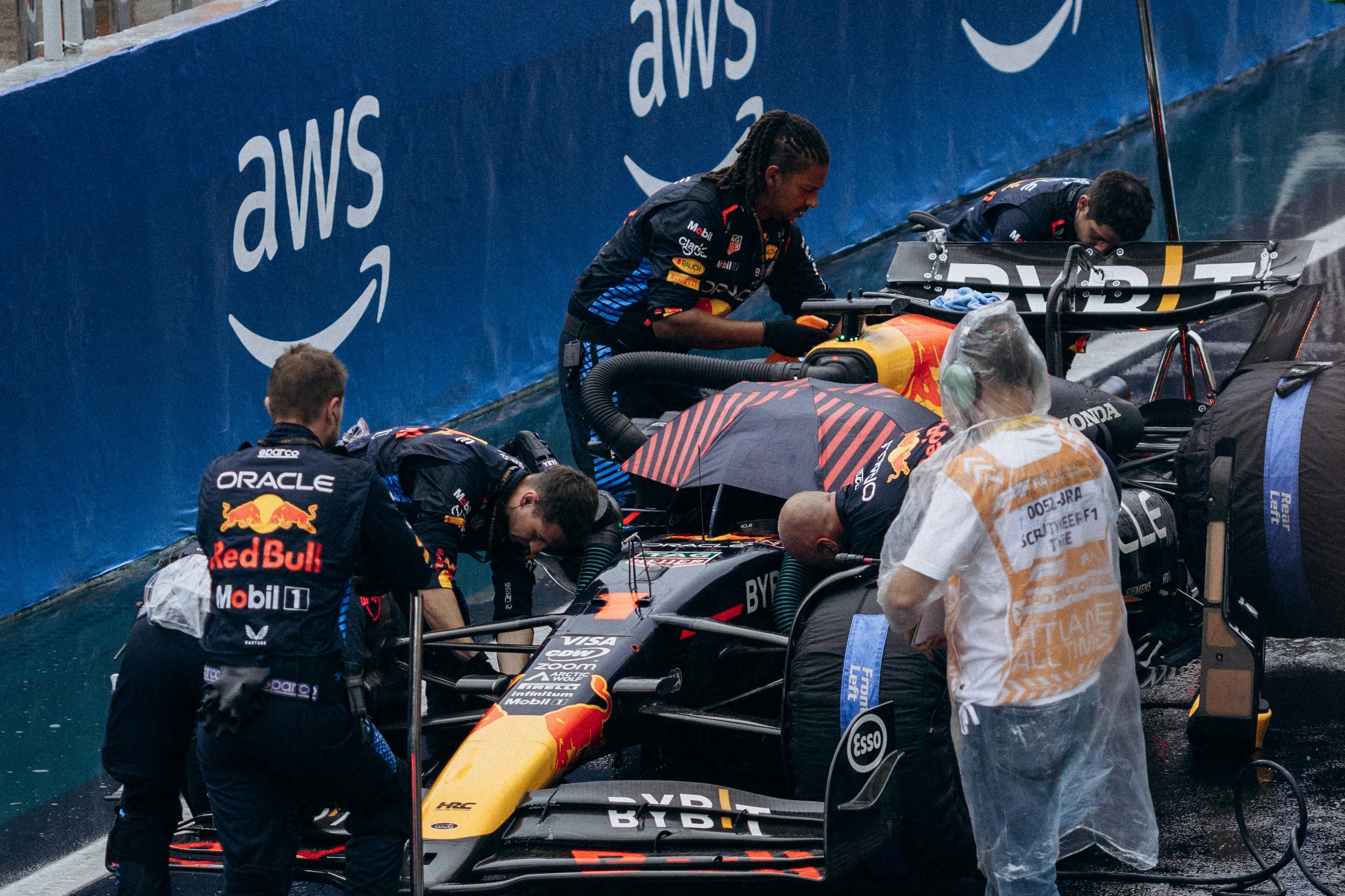 Red Bull F1 car in the pit lane with AWS branding on the barriers