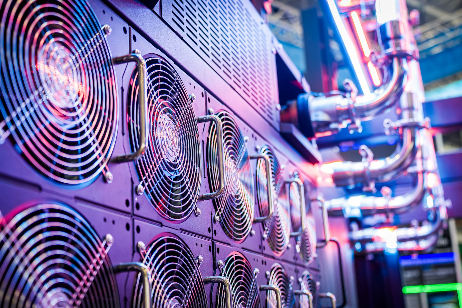 Rows of cooling fans and pipework inside a brightly lit server environment