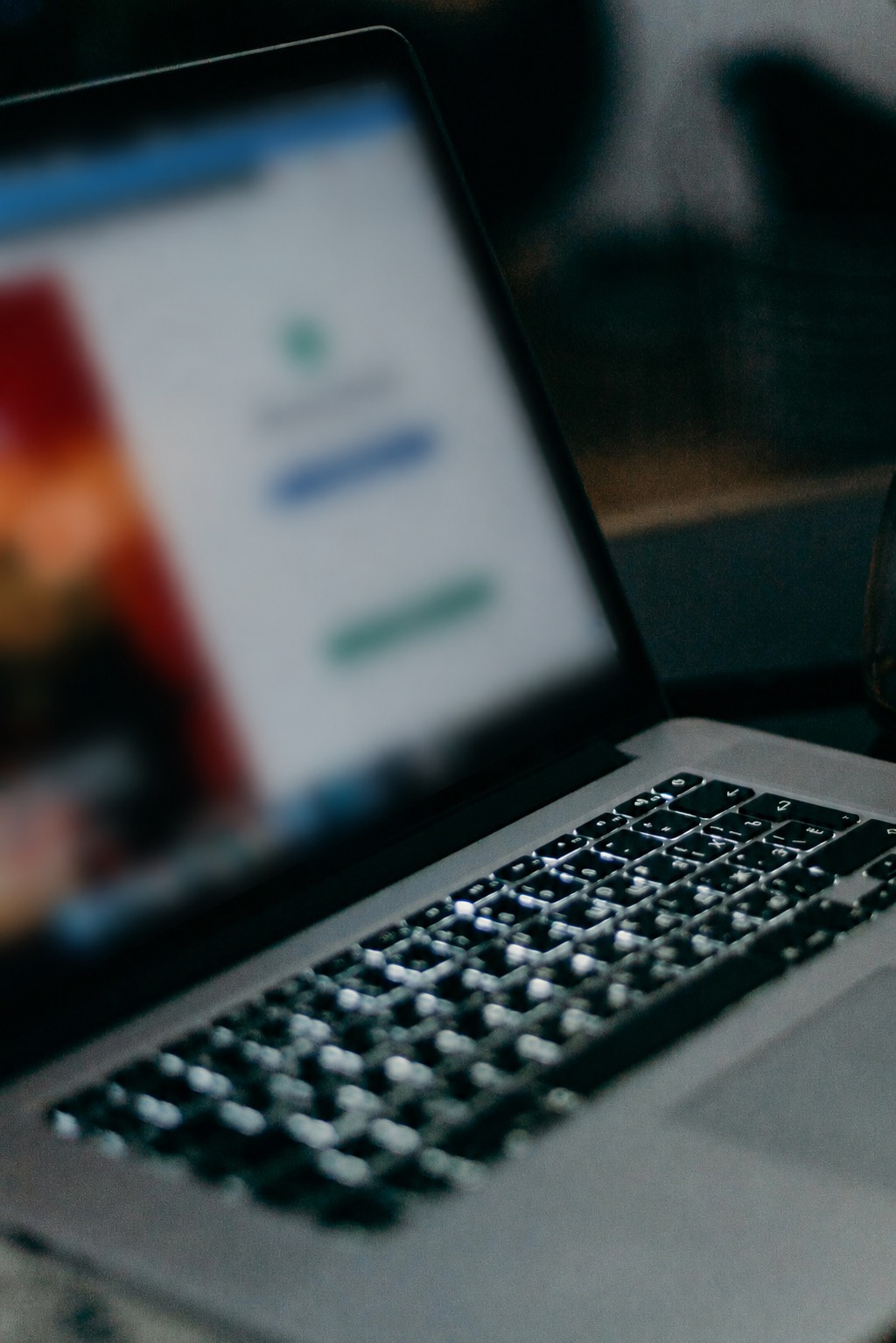 A blurred laptop screen and keyboard in low light
