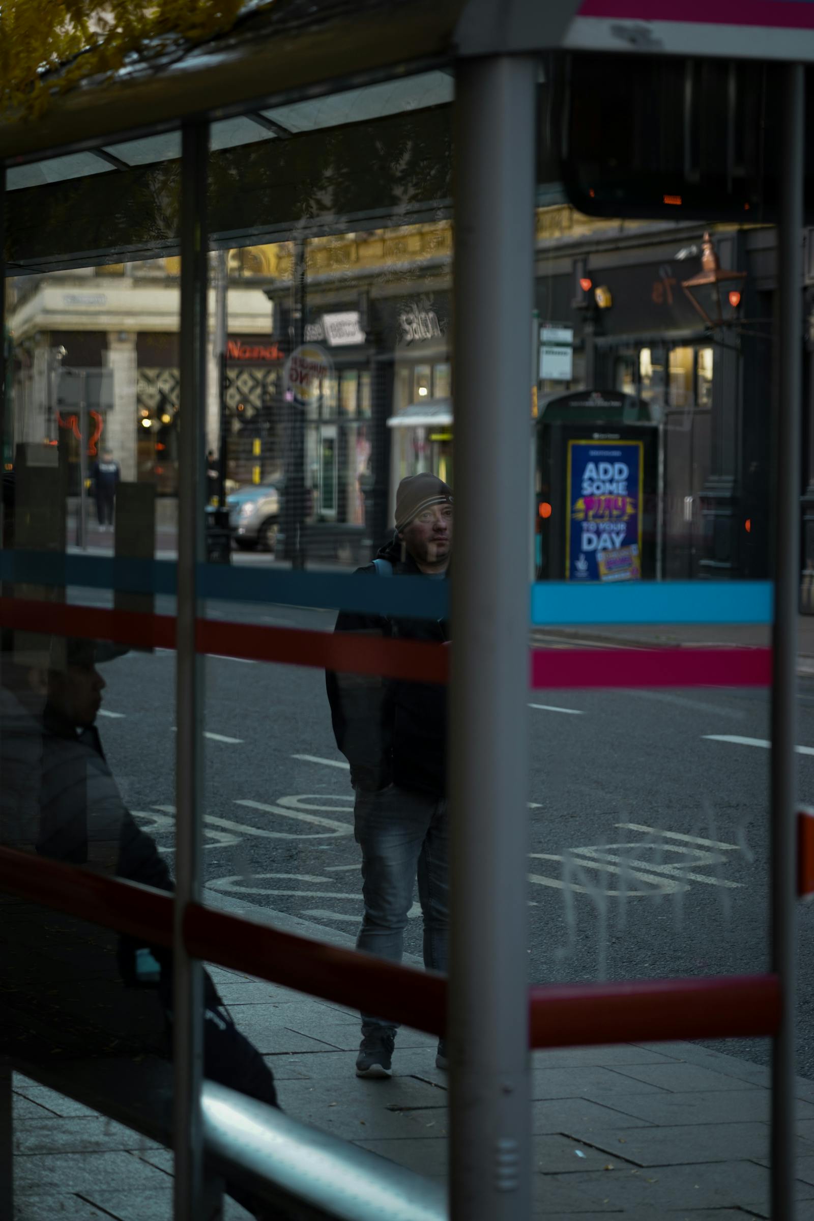People waiting at a London bus stop with city reflections around them