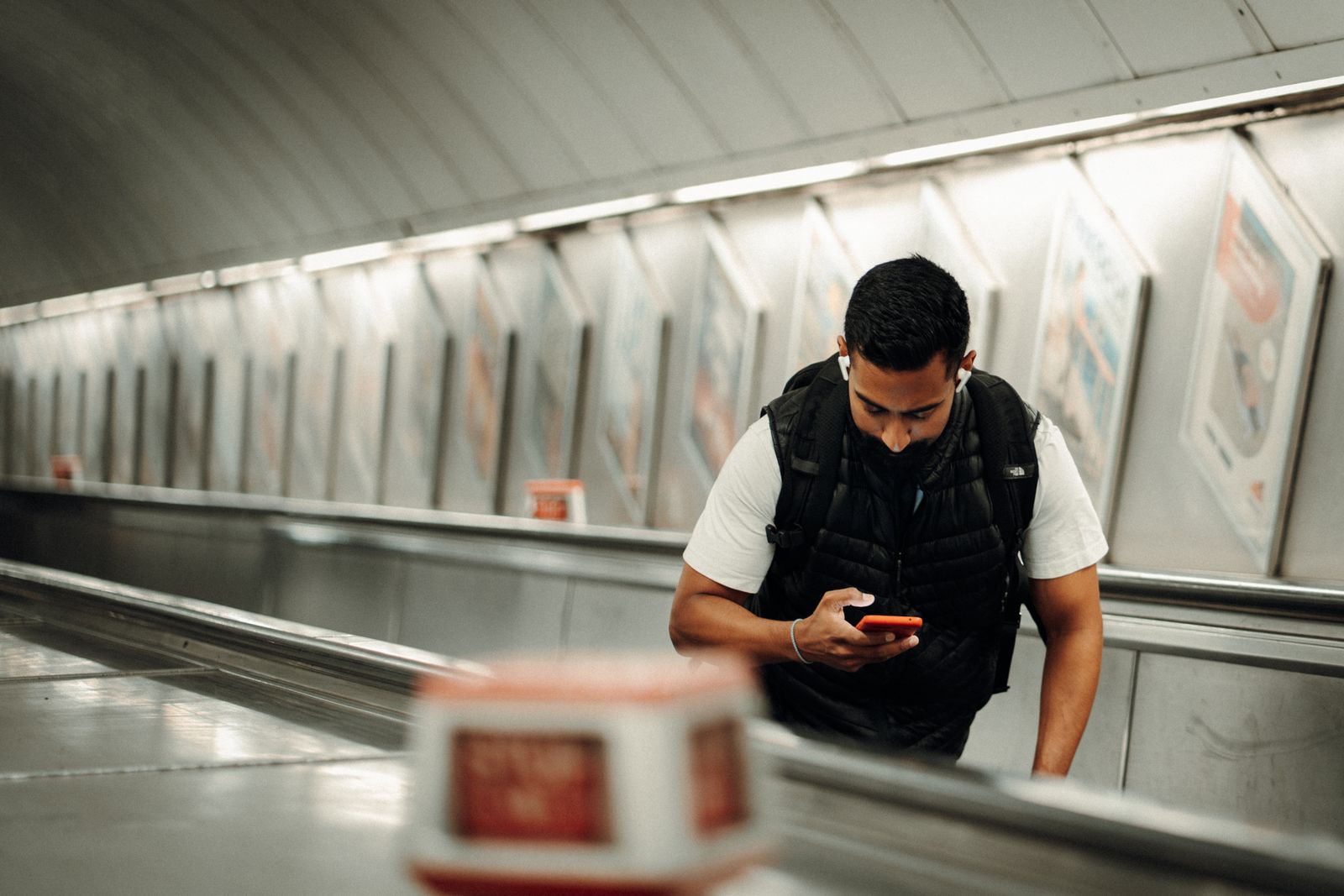 A commuter using a smartphone on an escalator in the London Underground
