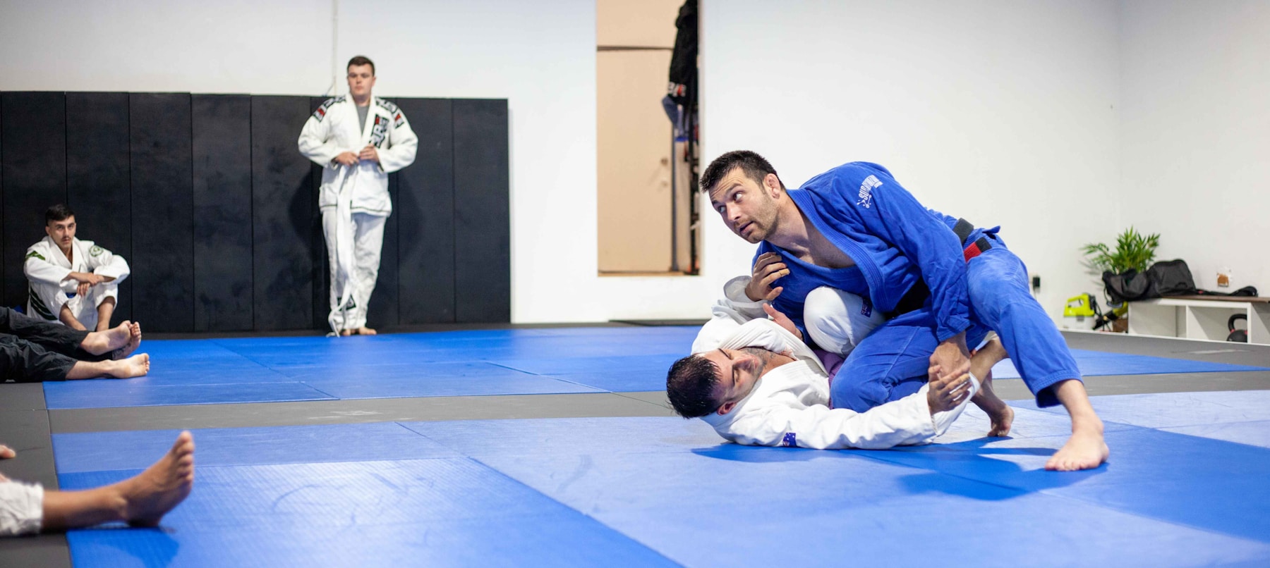 Brazilian jiu-jitsu practitioners training on the mat in a gym