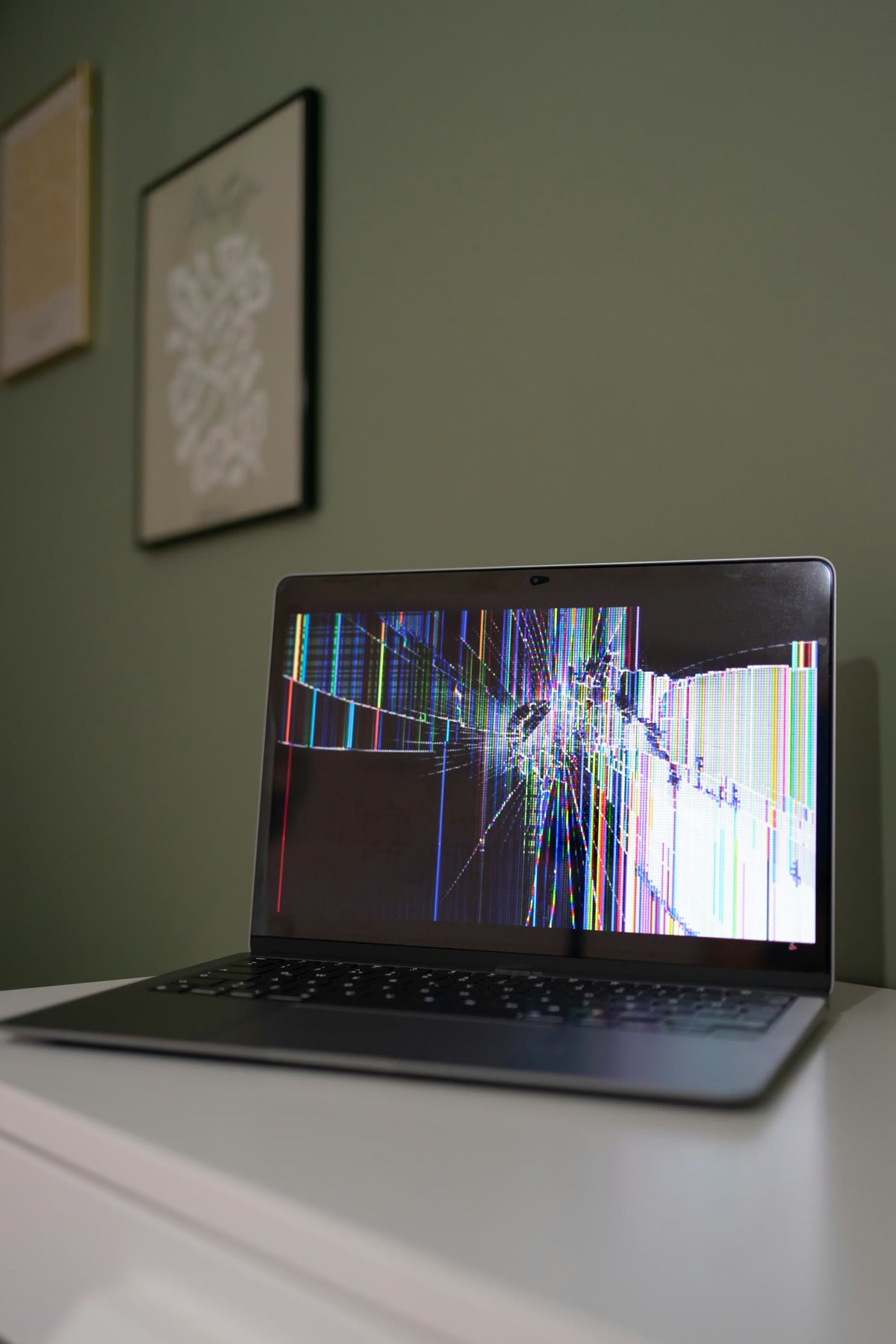 A laptop with a broken, glitched screen on a desk