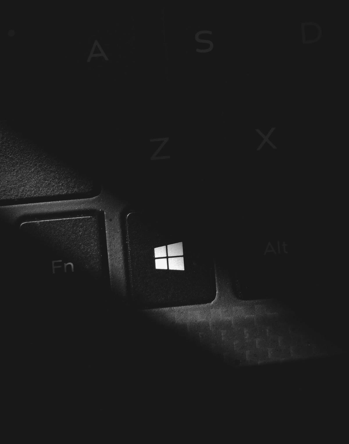 A dark close-up of a keyboard focused on the Windows key